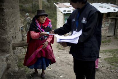 Una mujer indígena quechua entrega su tarjeta de identificación antes de emitir su voto en Iquicha, durante las elecciones generales de Perú.