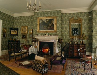 Salón de estilo eduardiano con papel tapiz verde de William Morris.