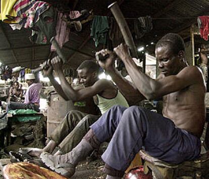 Dos hombres golpean planchas de acero para hacer sartenes en un barrio de Nairobi, capital de Kenia.