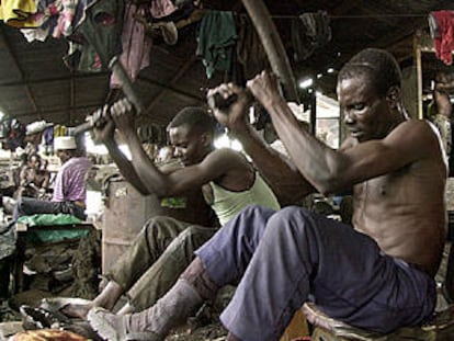 Dos hombres golpean planchas de acero para hacer sartenes en un barrio de Nairobi, capital de Kenia.