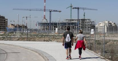 Dos personas caminan frente a viviendas en construcción en El Cañaveral.