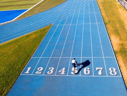 Canada British Columbia, Vancouver  aug 8 2022.  a single male runner exercising on running track .   all marks and names have been removed from this high school track lanes.  photographer droned photo'ed  himself .