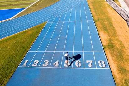 Canada British Columbia, Vancouver  aug 8 2022.  a single male runner exercising on running track .   all marks and names have been removed from this high school track lanes.  photographer droned photo'ed  himself .