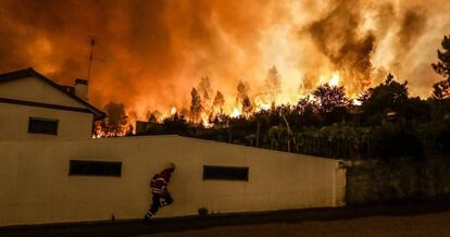 Un bombero se protege del incendio tras unas casas en Pampilhosa da Serra.