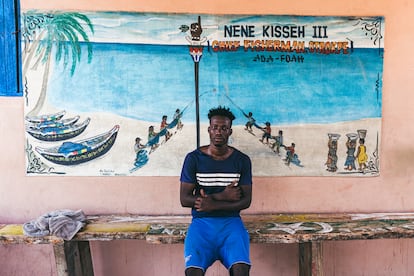 Nene Kissed III posa delante de un panel pintado a las afueras de su comunidad. "Los hombres forman la flota del barco, las mujeres limpian y venden el pescado, y los niños,  bien ayudan a las madres, bien entran en el agua a trabajar", explica.