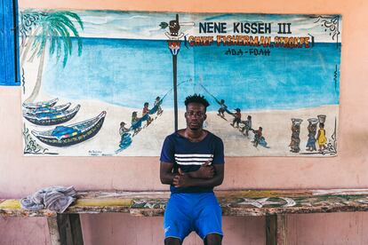 Nene Kissed III posa delante de un panel pintado a las afueras de su comunidad. "Los hombres forman la flota del barco, las mujeres limpian y venden el pescado, y los niños, bien ayudan a las madres, bien entran en el agua a trabajar", explica.