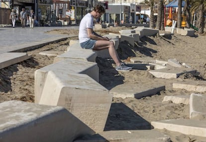 A person reads while sitting on a piece of the broken promenade in  Xàbia.