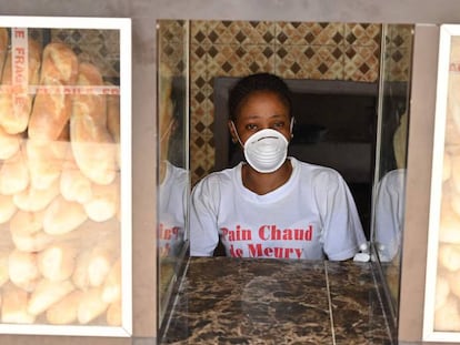 Una mujer luce una mascarilla preventiva frente al coronavirus mientras vende pan cerca de Abiyán. 