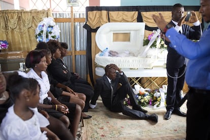 Un hombre permanece sentado frente al ataúd de su madre durante el funeral en la iglesia de St. Anne en Puerto Príncipe, Haití.