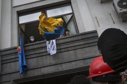 De acuerdo con RIA Novosti, varios miles de partidarios de la federalización se han congregado delante del edificio reclamando, entre otras cosas, la celebración de un referéndum y que se dé al ruso estatus oficial. Muchos de ellos portan banderas rusas. En la imagen, un manifestante tira la bandera de Ucrania por la ventana del edificio tomado.