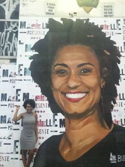 Leticia posa em muro no centro de São Paulo com lambe em homenagem à Marielle.