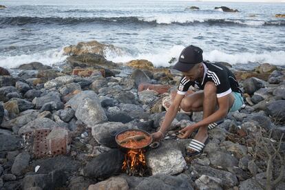 Un joven termina de cocinar un tayín de pescado, capturado anteriormente por sus compañeros, en la playa El Trampolín, cerca de playa de Benítez. Entre 17 y el 19 de mayo, más de 9.000 personas entraron en Ceuta a nado, bordeando los espigones fronterizos o a través del vallado que separa la ciudad de Marruecos. Más de 2.000 adultos están aún en la ciudad, muchos durmiendo a la intemperie.