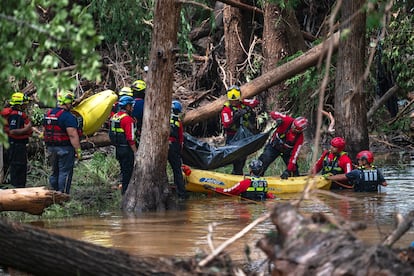 Bomberos de Ciudad Acuña suben un cuerpo a una balsa en el río Guadalupe, durante la emergencia en Texas.