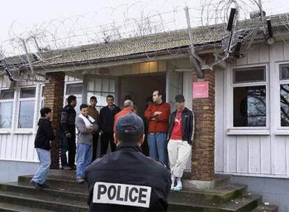 Un agente de la policía, frente a un grupo de extranjeros del campo de retención de inmigrantes de Vincennes, en París.