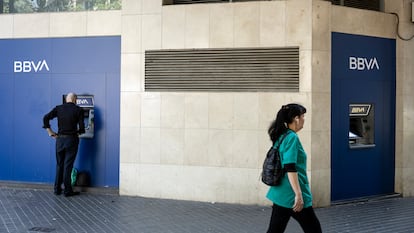 Un hombre saca dinero del cajero en una oficina bancaria del BBVA en el Eixample.  