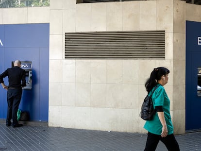 Un hombre saca dinero del cajero en una oficina bancaria del BBVA en el Eixample.