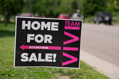 A for sale sign stands outside a single-family residence