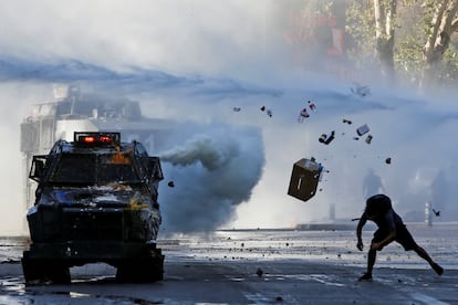 Un manifestante arroja artículos contra un vehículo blindado durante una protesta contra el gobierno de Chile en Santiago, Chile, 30 de diciembre de 2019.