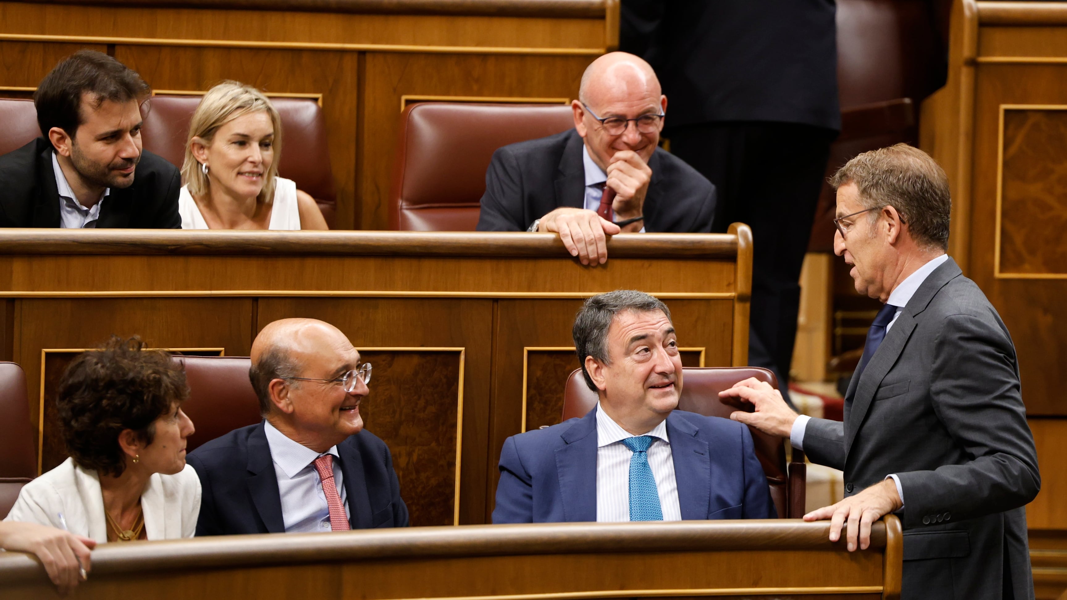 El líder del PP, Alberto Núñez Feijóo, de pie, charla con Aitor Esteban en el Congreso bajo la mirada de los diputados del PNV en 2023. 