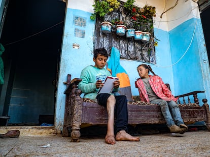 Abdul Rahman Al-Safar, wounded by a cluster bombardment, studies with his sister in the courtyard of their house in the village of Al-Nairab, eastern Idlib.