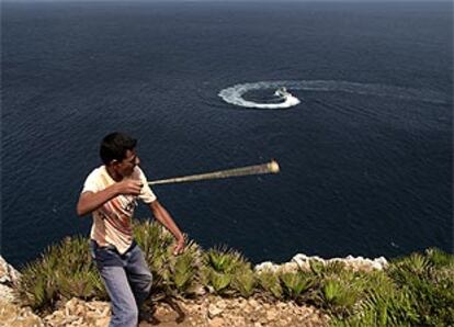 Un joven marroquí lanza una piedra con una honda hacia una patrullera de la Guardia Civil en las inmediaciones del islote Perejil.