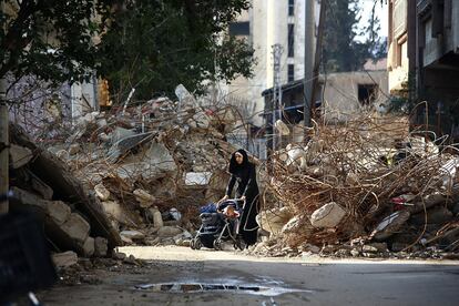 Una mujer camina junto a su hijo entre los escombros de la ciudad siria de Douma.