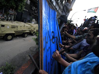 Soldados egipcios protegen la Embajada de Israel, ayer en El Cairo. En frente, los manifestantes hacen ruido con barras de hierro para protestar por la muerte de militares egipcios en el Sinaí.