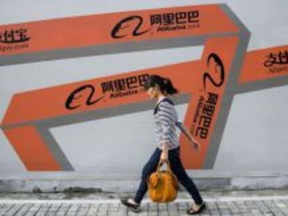 Una mujer camina junto a una pancarta publicitaria de Alibaba