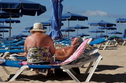 Dos turistas ingleses toman el sol en la playa de Levante de Benidorm.