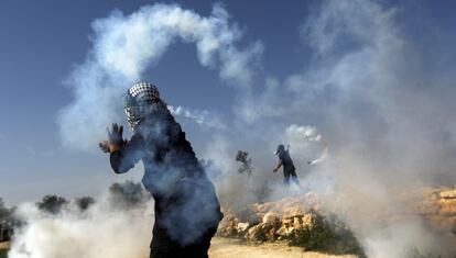 Unos palestinos devuelven con sus hondas botes de gases lacrimógenos lanzados por soldados israelíes durante un acto de protesta contra el muro de separación construido por Israel, en la localidad cisjordana de Bilin, cerca del asentamiento israelí de Kfar Sifer (al fondo).