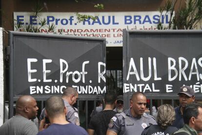 Policiais controlam a entrada da escola, enquanto multidão se aglomera em busca de informações 