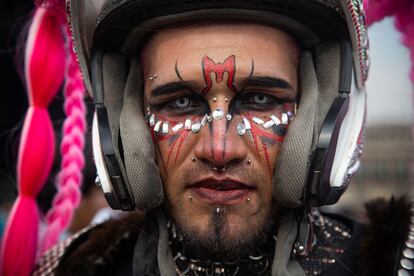 Un hombre que lleva un casco de motociclista y la cara pintada espera antes del concierto.