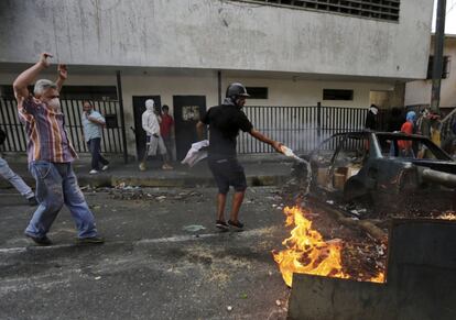 Manifestantes en contra del Gobierno de Nicolás Maduro prenden fuego a neumáticos y coches en el bloqueo de una carretera en pleno enfrentamiento con las fuerzas de seguridad, tras el intento de motín de los soldados.