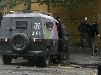 Un estudiante lanza piedras contra un vehículo de los carabineros chilenos en Santiago.