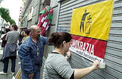 Simpatizantes de Batasuna colocan carteles en la entrada de su sede, que también es 'herriko taberna'.