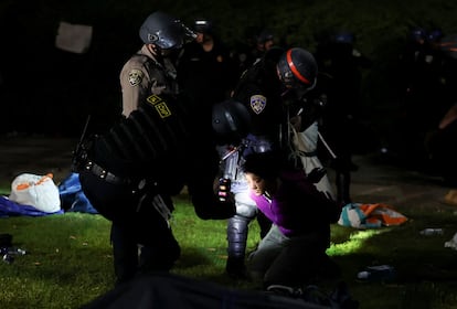 Un agente de policía utiliza un teléfono móvil para identificar  a un manifestante detenido en la Universidad de California de Los Ángeles.