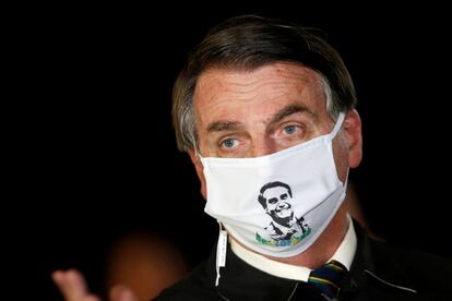 El presidente de Brasil, Jair Bolsonaro, habla con periodistas protegido con una mascarilla con su imagen, en el palacio de Alvorada (Brasil). El país se ha convertido en las últimas horas en el segundo más afectado del mundo por número de casos, con 330.890 positivos y 21.048 fallecidos.