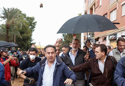 El rey Felipe VI es protegido por los escoltas durante el lanzamiento de barro a su llegada a Paiporta, este domingo. 