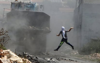 Um manifestante palestino lança uma garrafa cheia de tinta em uma escavadeira do exército israelense durante os confrontos depois uma manifestação contra a expropriação de terras palestinas por Israel, na aldeia de Kfar Qaddum.