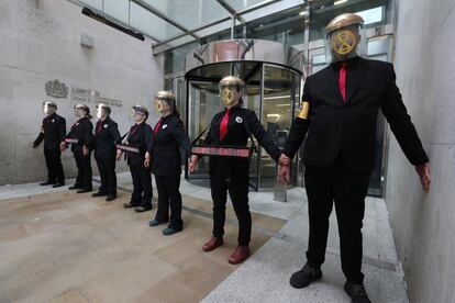 En el centro financiero de la capital, un grupo de trece activistas vestidos de traje negro, con las cabezas cubiertas con una especie de máscara transparente, se 'pegaron' con pegamento los unos a los otros y al propio edificio de la Bolsa, a fin de impedir el paso al interior. En la imagen, los manifestantes en la puerta de la Bolsa de Londres durante la protesta del grupo ecologista en Londres, Gran Bretaña, el 25 de abril de 2019.