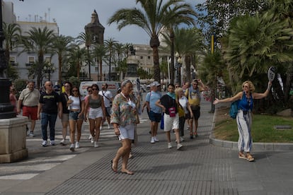 Un grupo de turistas pasea por la plaza de San Juan de Dios de Cádiz, dirigidos por una guía turística. 