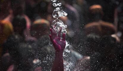 Detalle de agua cayendo sobre la mano teñida de rosa de un participante que baila en el festival Holi, que marca la llegada de la primavera, en Gauhati, (India).