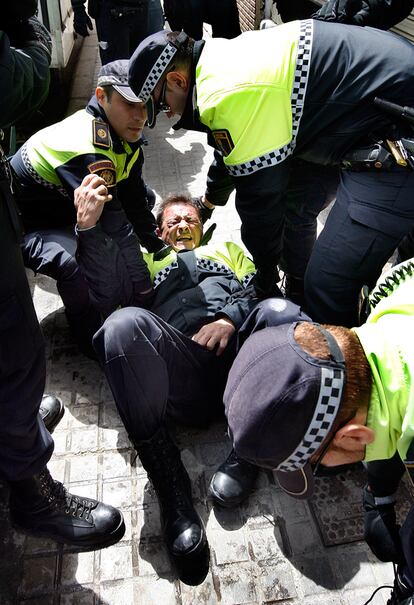 Un policía municipal es atendido por sus compañeros después de haber caído al suelo.