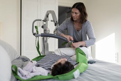 Assumpta Garrido, coloca a su hija en la grúa, para poder trasladarla de la cama, a final de marzo, en su casa, en Cabrera de Mar (Barcelona). 