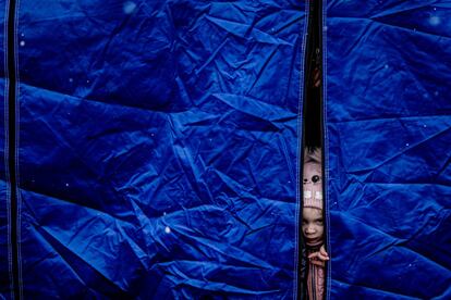 Una niña mira entre los plásticos de una tienda de campaña en Siret. Rumania solo ha vivido una crisis humanitaria similar a la actual: cuando decenas de miles de polacos ―entre ellos miembros del Gobierno― fueron acogidos por las autoridades rumanas justo después de que la URSS invadiera Polonia tras declararse la Segunda Guerra Mundial.