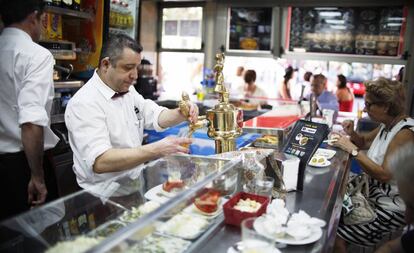 Un cambrer atén els clients en un bar.