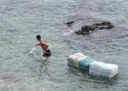 Un porteador intenta pasar mercancía hacia Marruecos, ayer, por la playa de Benzú.