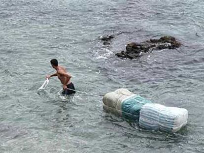 Un porteador intenta pasar mercancía hacia Marruecos, ayer, por la playa de Benzú.