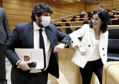 El presidente de Murcia, Fernando López Miras, saluda con el codo a la ministra de Política Territorial, Carolina Darias, en la comisión de comunidades autónomas en el Senado.