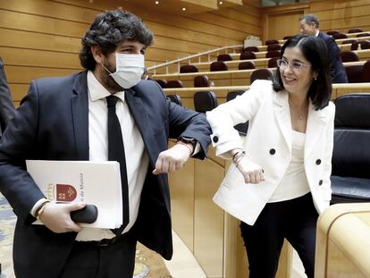 El presidente de Murcia, Fernando López Miras, saluda con el codo a la ministra de Política Territorial, Carolina Darias, en la comisión de comunidades autónomas en el Senado.